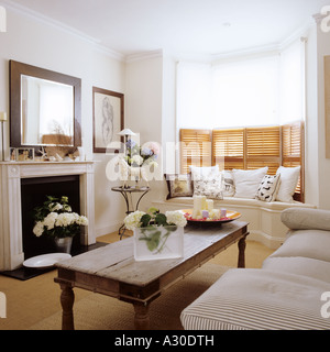 Sitting room with wooden coffee table, window seat and shutters Stock Photo