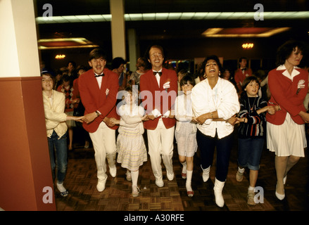 red coats with guests singing and dancing hand in hand at butlins Stock Photo