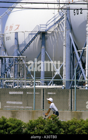 tokyo japan a young boy on a bicycle passes the industrial plant works outside of tokyo Stock Photo