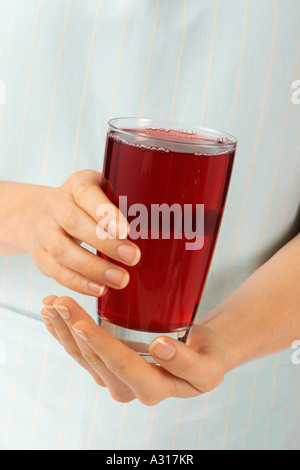 WOMAN HOLDING GLASS OF POMEGRANATE JUICE Stock Photo