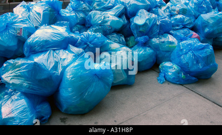 Recyclables in blue plastic bags waiting for hauler to pick up and take to transfer station Stock Photo