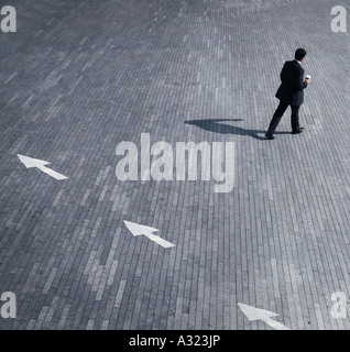 business concept of a man walking in the opposite direction of arrows Stock Photo