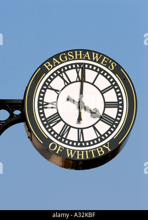 Bagshawe's of whitby exterior bracket clock, black and white with gold lettering and large clock hands, four o clock, in whitby north yorkshire uk Stock Photo