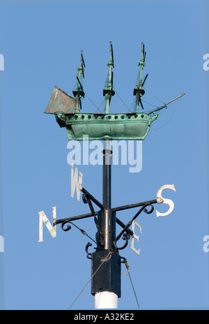 Copper galleon weather vane,wind direction indicator with verdigris patina, mounted on black metal pivot with cardinal points, in blue sky whitby uk Stock Photo