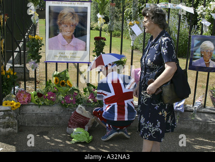 man wearing union jack clothes attaches flowers to fence at kensington palace in mourning for princess diana Stock Photo