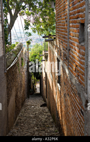 MEXICO San Miguel de Allende Narrow sidewalk between a stone wall and brick building on steep hill above town Stock Photo