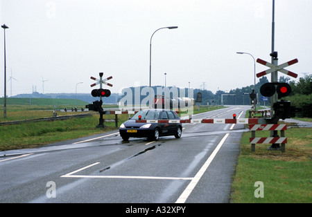 A car being driven though the closed gates on a railway level crossing Stock Photo