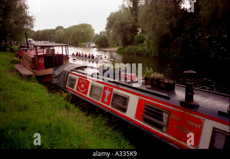 Rowers on a university womens crew team row past houseboats on the River Cam in Cambridge England Stock Photo