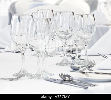 Wine glasses on a white tablecloth with place table settings Stock Photo