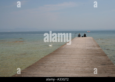 Contemplating the beautiful clear water of  Lake Garda from a pier on the Sirmione peninsula Veneto, Italy. Stock Photo