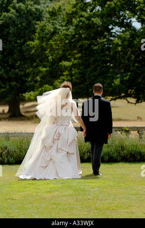 wedding couple walking across field Stock Photo