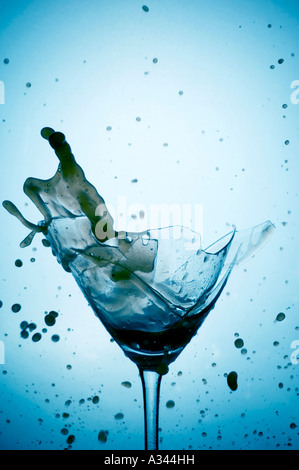 Powerful Splash breaking a martini glass , a conceptual image about alcohol addiction Stock Photo