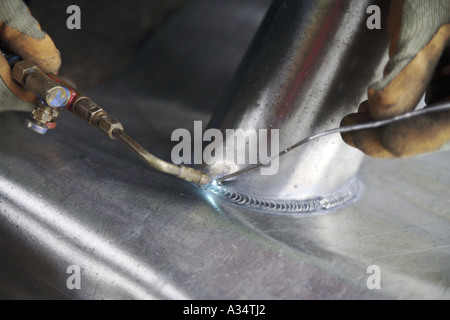 Skilled lead worker burns or welds a joint on a lead pipe collar Stock Photo