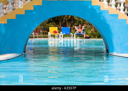 Tourist relaxing and sunbathing on a sun bed beside a pool, Trinidad, Cuba Stock Photo