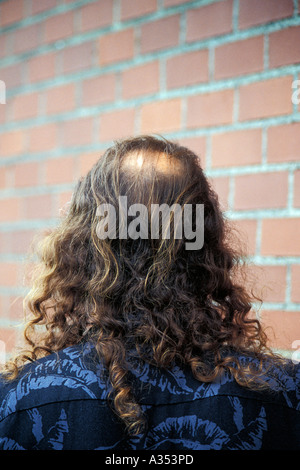 Back view of man s head with bald spot and long shoulder length curly hair Stock Photo