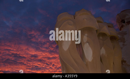 Architectural sculptures on the roof of La Pedrera apartment building set against richly illuminated clouds at sunset Barcelona Stock Photo
