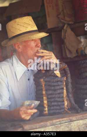 Nazare Bahia Brazil Man selling tobacco rope smoking a cigarette and  wearing a straw hat Stock Photo