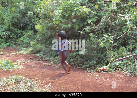 A Ukre village Brazil Kayapo child with black body paint and blue beads running through the forest Xingu Indigenous Reserve Stock Photo