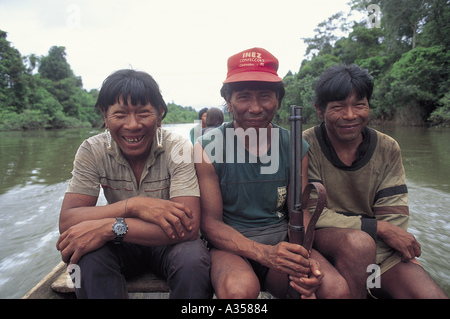 A Ukre Village Brazil Three smiling Kayapo men with a rifle in a canoe Stock Photo
