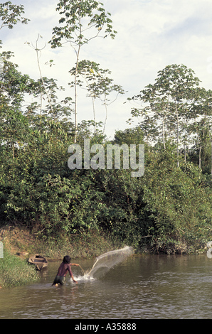 A Ukre Village Brazil young Kayapo man fishing with a net with a canoe behind Para State Stock Photo