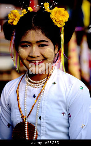 Young woman  at Pwe religious festival prepares to dance the part of a 'Nat's wife' wears flowers in hair and tanaka on her face Stock Photo