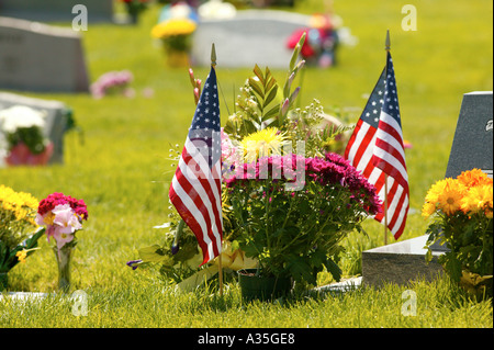 Flowers and American flags at a grave in a cemetery on Memorial Day Stock Photo