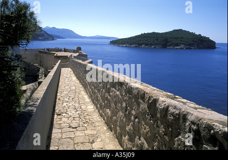 Tourists on Thirteenth Century Stone Parapet City Wall Surrounding ancient town Dubrovnik Overlooking the Adriatic Sea Lokrum Stock Photo
