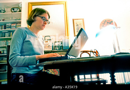 Young Adult, Woman, Working From Home looking at Laptop Computer Screen, Alone Living room Internet, busy Journalist, Profile, inside Stock Photo