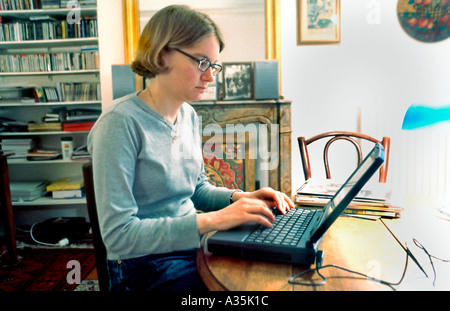 Young Adult Gritty, Woman Sitting, Looking at Laptop Computer  Screen, in Living Room Alone at Home Office, Night, people working, newspaper reporter Stock Photo