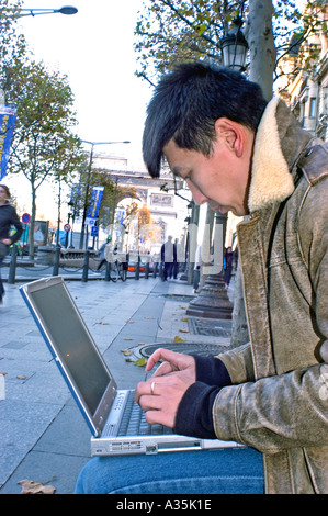 Paris FRANCE, Man on Street , Looking at Laptop Screen, Chinese Tourist Sitting Outside in profile, student France, people working, young person Stock Photo