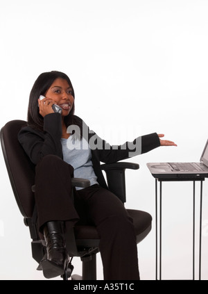Smiling African American businesswoman talking on mobile phone with hand extended in welcoming gesture, USA Stock Photo