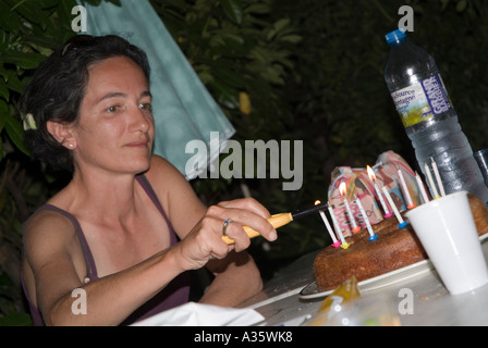 Woman lighting birthday candles of her 11 years son birthday cake Stock Photo