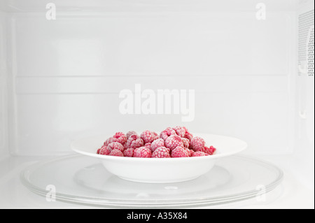 Plate Of Frozen Raspberries In Microwave Oven Stock Photo