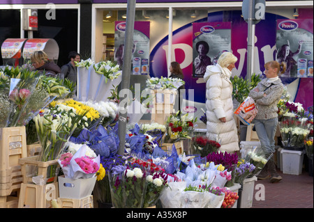 two women talk beside bunches of flowers for sale on a flower stall grafton street dublin Stock Photo