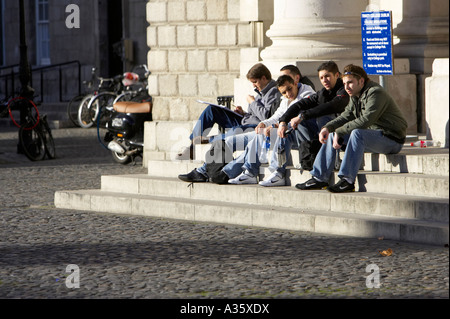 foreign students sitting on steps in parliament square Trinity College Dublin University of Dublin Stock Photo