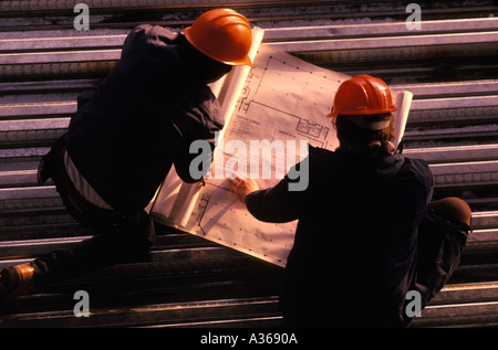 construction workers looking at plans on metal sub flooring of high rise Stock Photo