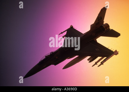 model US Air Force F 16 jet fighter in partial silhoette against blue purple yellow background Stock Photo