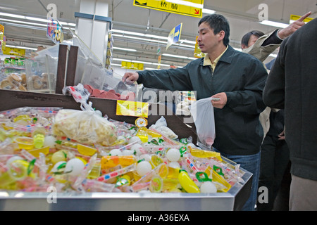 CHINA BEIJING Male Chinese shopper helping himself to cookies in Wumart an upscale supermarket in Beijing Stock Photo