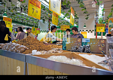 CHINA BEIJING Clerk helps Chinese customers with dried fruits and sweets in Wumart an upscale supermarket in Beijing Stock Photo