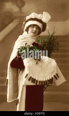 Early 1920's portrait of a pretty glamorous young woman in a Christmas outfit holding mistletoe, U.K. Stock Photo