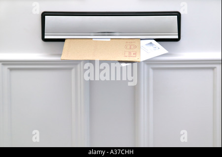 Two letters sticking out of a letterbox on a white door space for copy Stock Photo