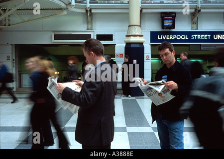 People reading newspaper while waiting at Liverpool street station London England Britain UK Stock Photo