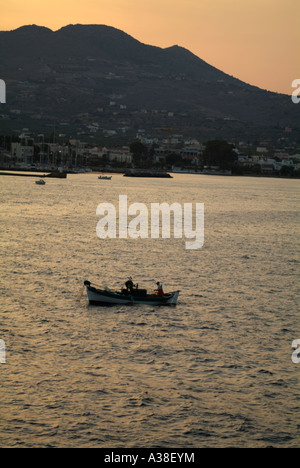 A small kaiki fishing boat collecting fishing nets at dawn outside Aegina harbour, Isle of Aegina, Greece Stock Photo