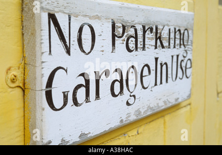 Stylish handpainted notice on yellow door or wall proclaiming No parking Garage in use Stock Photo