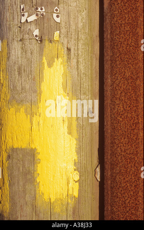 Abstract colours and textures formed by weathered wood paint rusting metal and broken plastic signs on pole Stock Photo