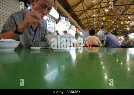 Local man eating a bowl of noodles at Maxwell Hawker Centre, Singapore Stock Photo