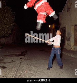 A young girl hits a Santa Claus Father Christmas pinata with a stick in Mazatlan Sinaloa Mexico Stock Photo