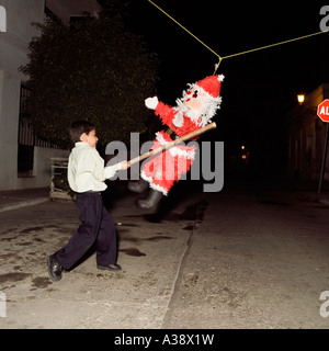 A young boy hits a Santa Claus Father Christmas pinata with a stick in Mazatlan Sinaloa Mexico Stock Photo