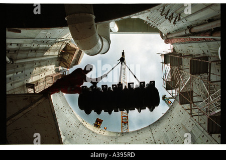 Workman in hard hat lowering drilling equipment into a stormwater culvert. Stock Photo