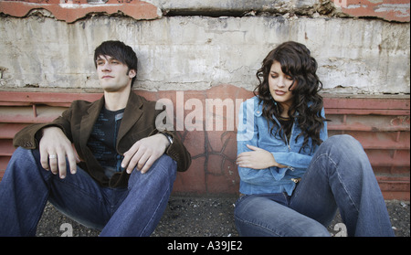 Young trendy couple sitting on the sidewalk Stock Photo